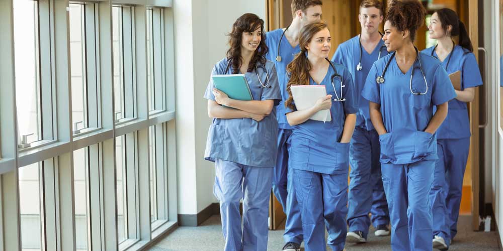 Healthcare students walk down a hospital hall.