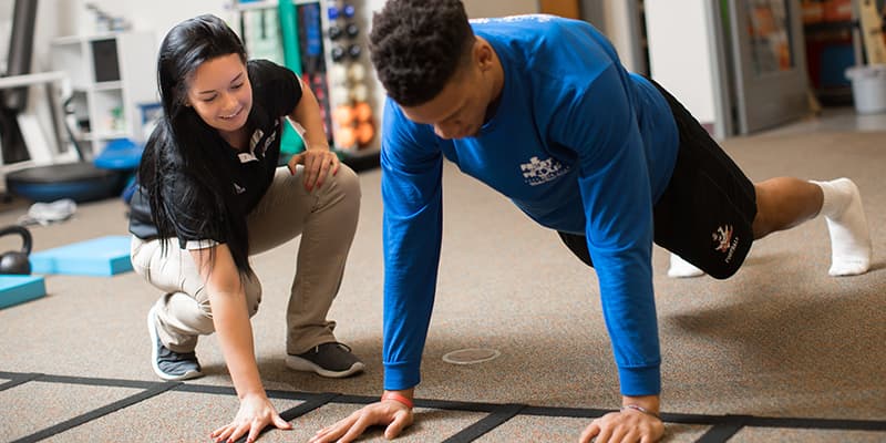 An athletic training students works with an athlete.