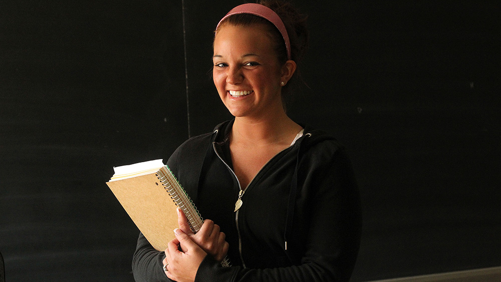 A smiling student poses with a book.