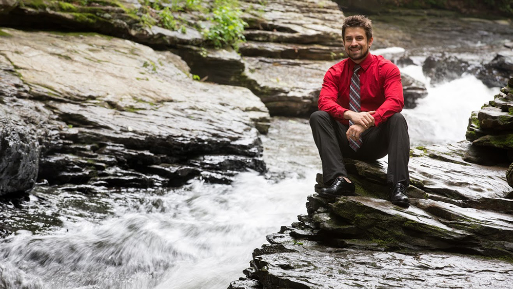 A Cal U student sits on rocks and Laurel Mountain park.