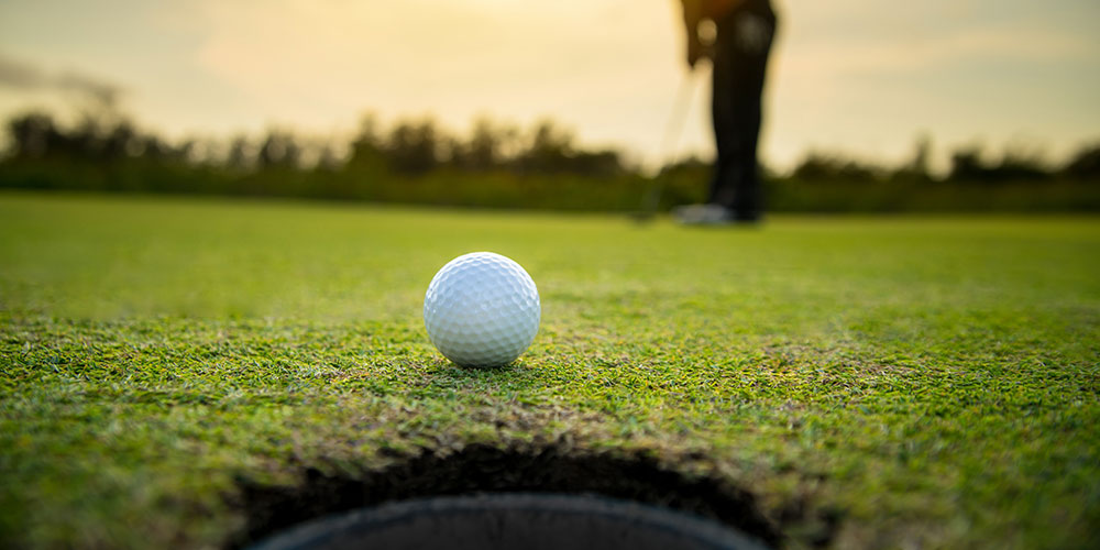A golf ball rolling towards the hole.