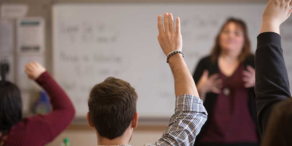 An arabic language and cultures student raises his hand in class.