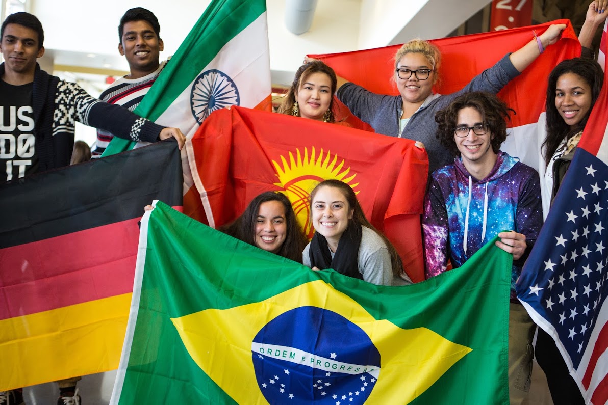 A group of students each hold a flag from another country.