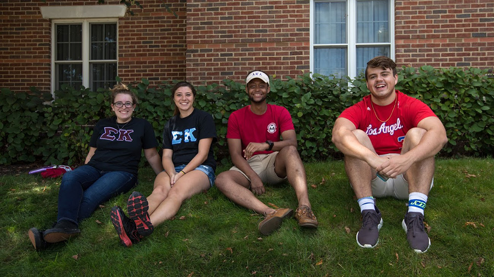 Students sit on lawn ourtside of residence halls.
