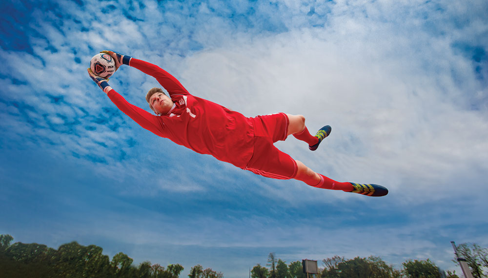 Lucas Exner catches a soccer ball by leaping into the air.