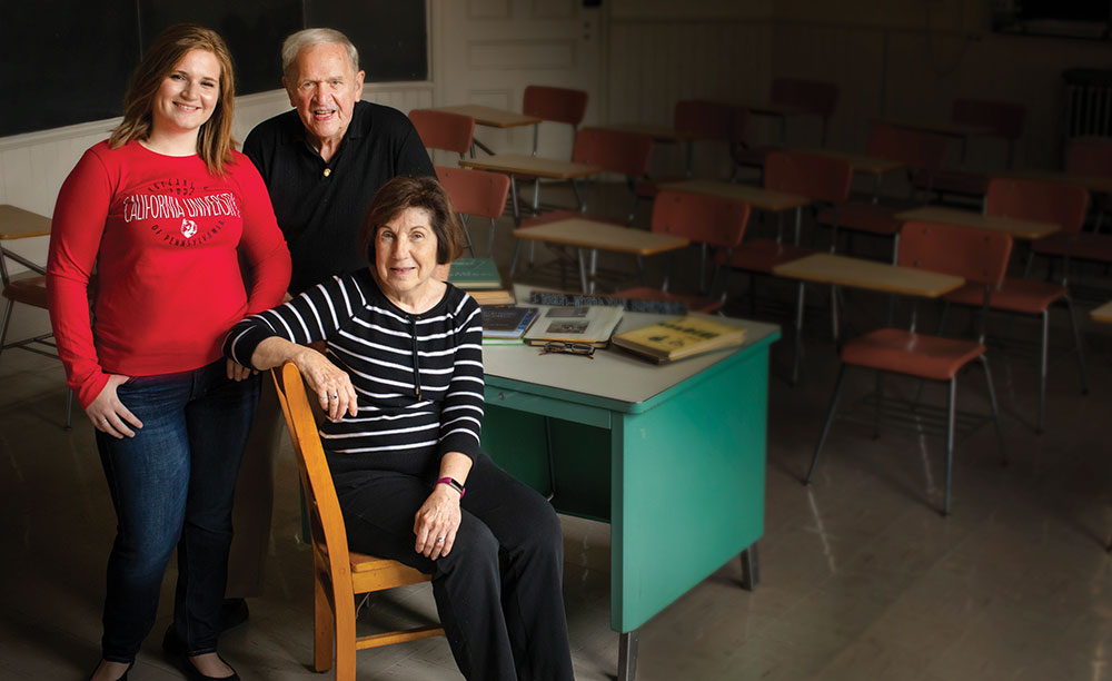 Rachel Wilkinson sits with family in a classroom posing for a portrait.